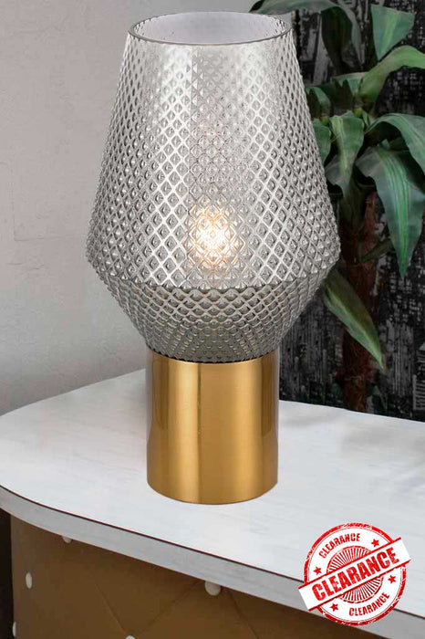Grey smoke glass table lamp with antique gold base on a white table