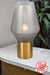 Grey smoke glass table lamp with antique gold base on a white table