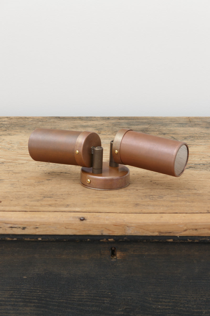 Fat Shack Vintage's Aged Copper double spot wall light uninstalled on a timber bench. 