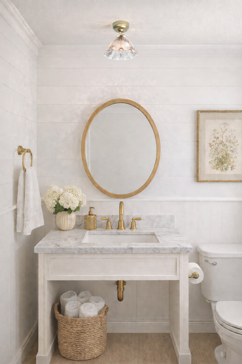 Large pleated clear glass shade with frilled edge detailing on a gold batten holder in a powder room. 