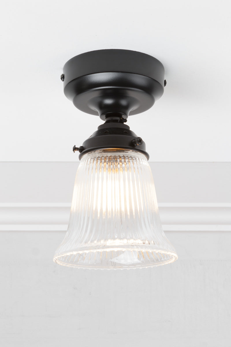 Small clear glass shade with ribbed shade on a black batten holder. 