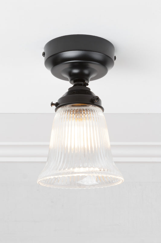 Small clear glass shade with ribbed shade on a black batten holder. 
