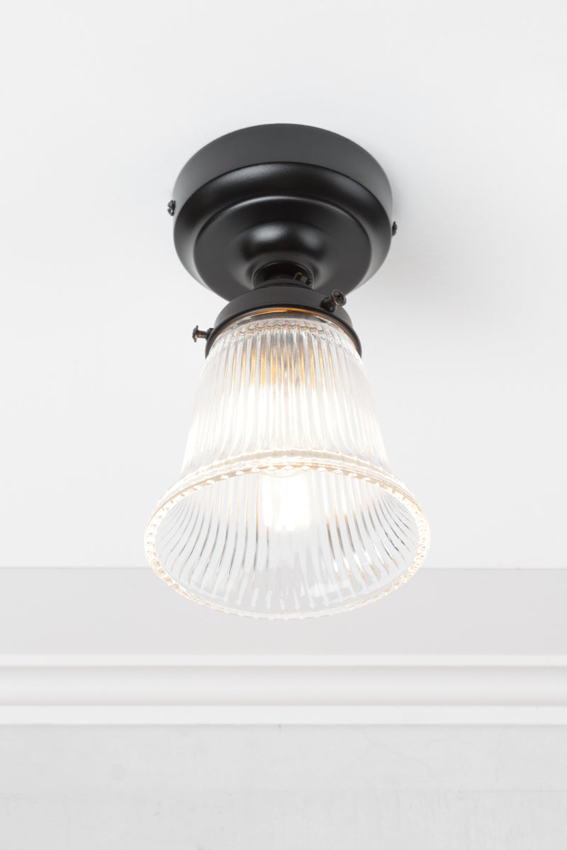 Upward view of the small clear glass shade with ribbed shade on a black batten holder. 