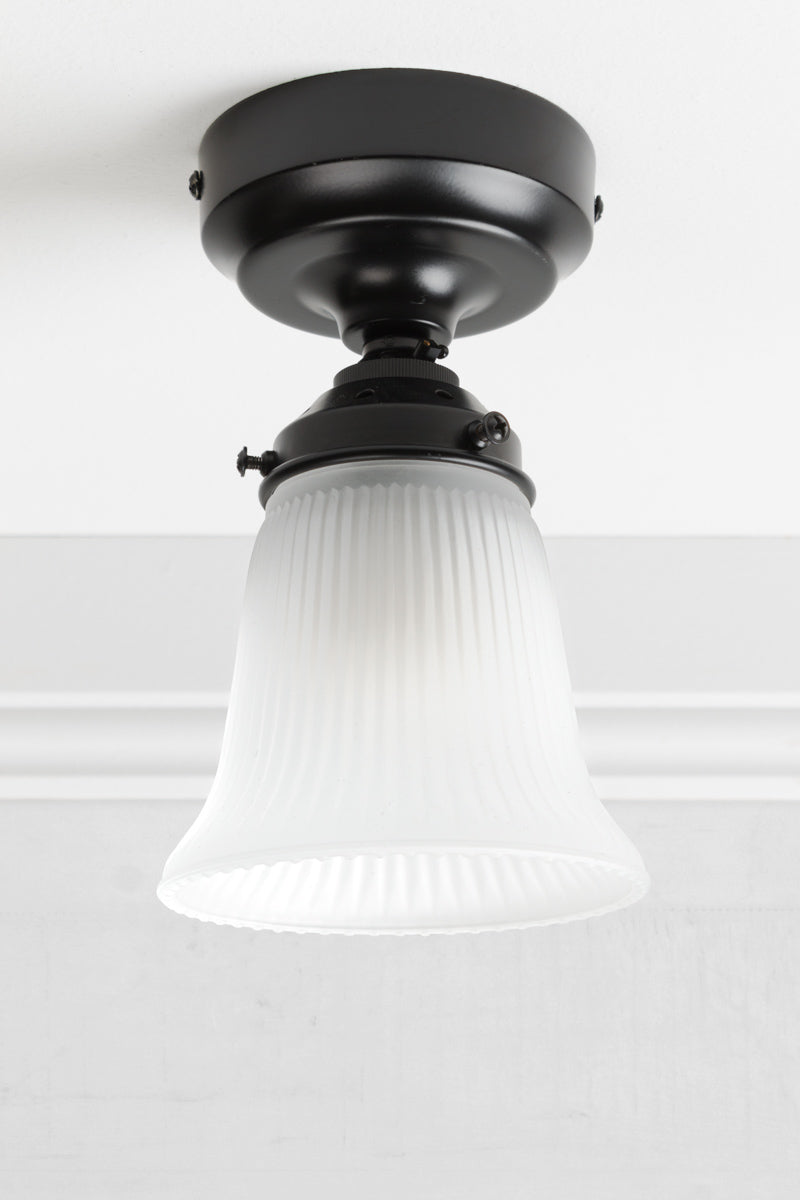 small opal glass shade with ribbed shade on a black batten holder with light turned off. 