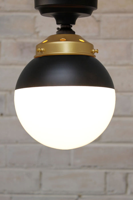 Crown Sphere Flush Mount Light black mount with a gold gallery and a black and opal shade