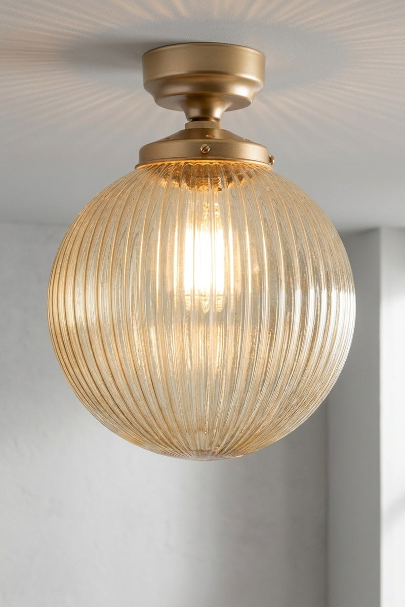 Medium amber reeded glass shade paired with a gold/brass batten holder on a white, shiplap wall. 