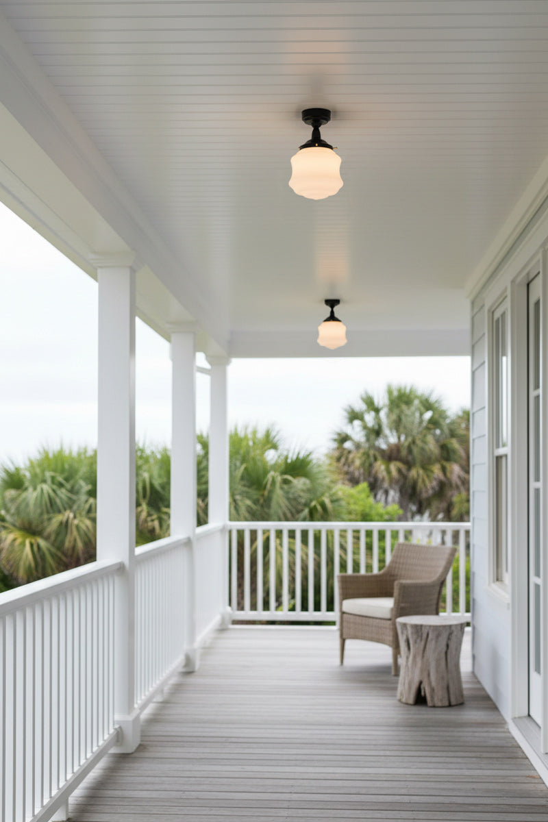 Two schoolhouse style opal shades on on flush mount fixtures installed under a verandah. 