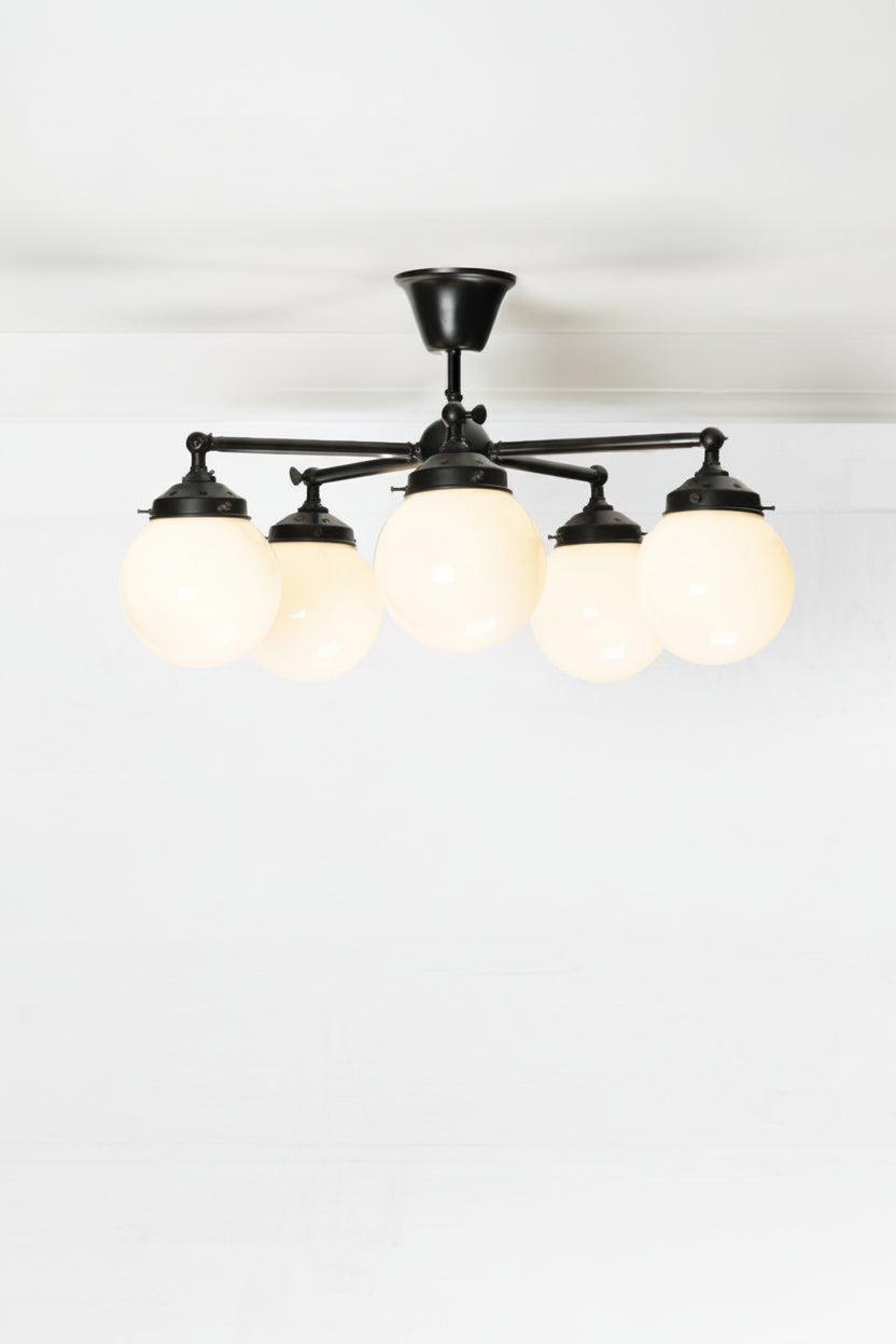 Five arm flush mount light in black with opal glass ball shades. 