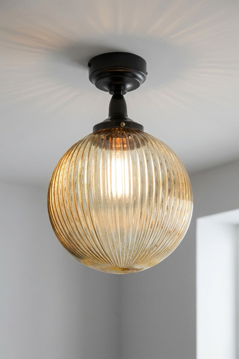 Medium amber reeded glass ball shade on a black flush mount that is IP rated. 