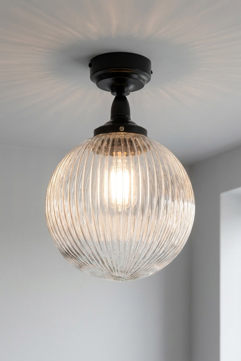 Medium clear reeded glass ball shade on a black flush mount that is IP rated. 