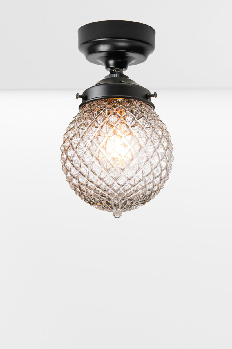 Clear glass ball shade with vintage detailing on a black batten holder. 
