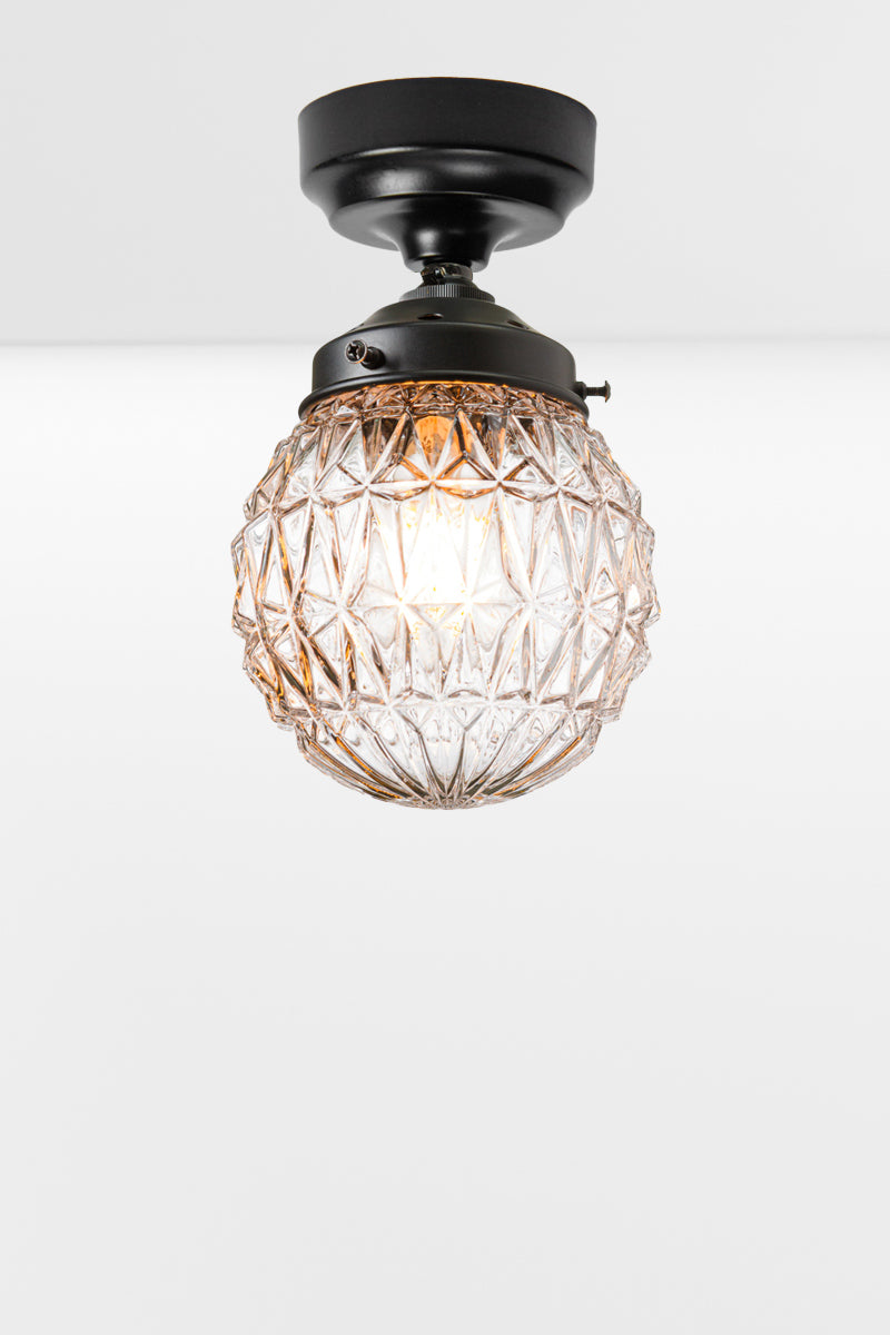 Clear glass ball shade with geometric vintage deatiling, on a black batten holder. 