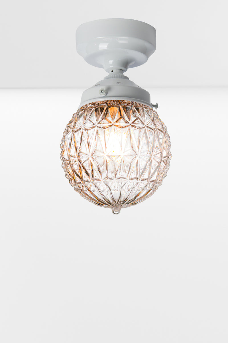 Clear glass ball shade with geometric vintage deatiling, on a white batten holder. 