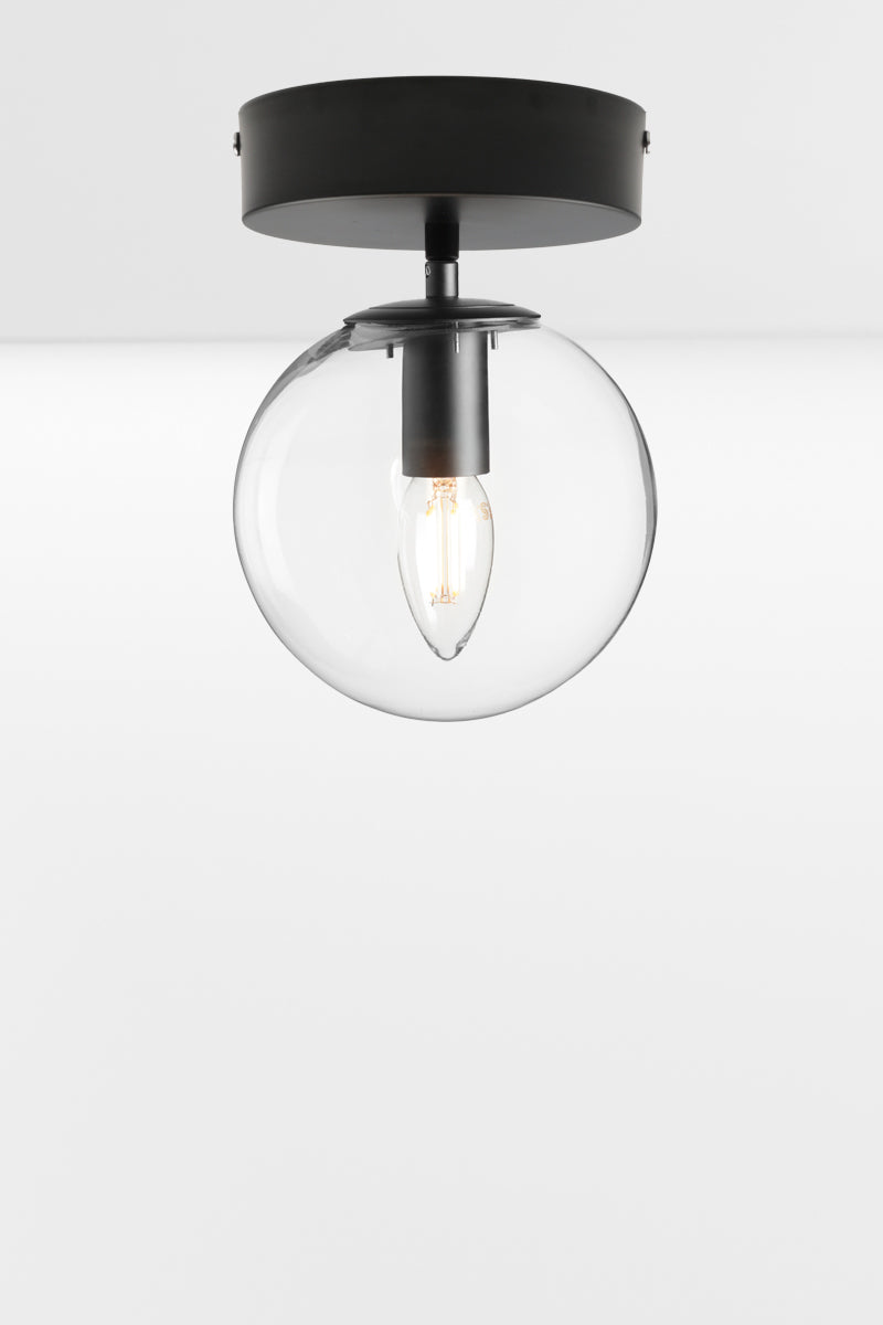 Clear glass orb shade with a black flush mount, using a candle bulb.