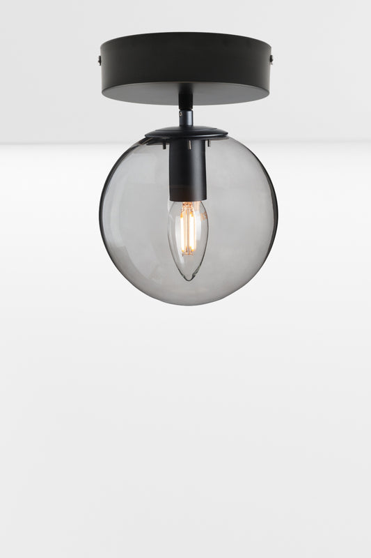 Glass orb shade with a grey finish on a black flush mount, using a candle bulb.