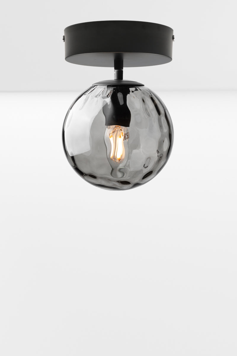 Orb glass shade in grey with a dimpled detailing on a matt black flush mount fixture. 