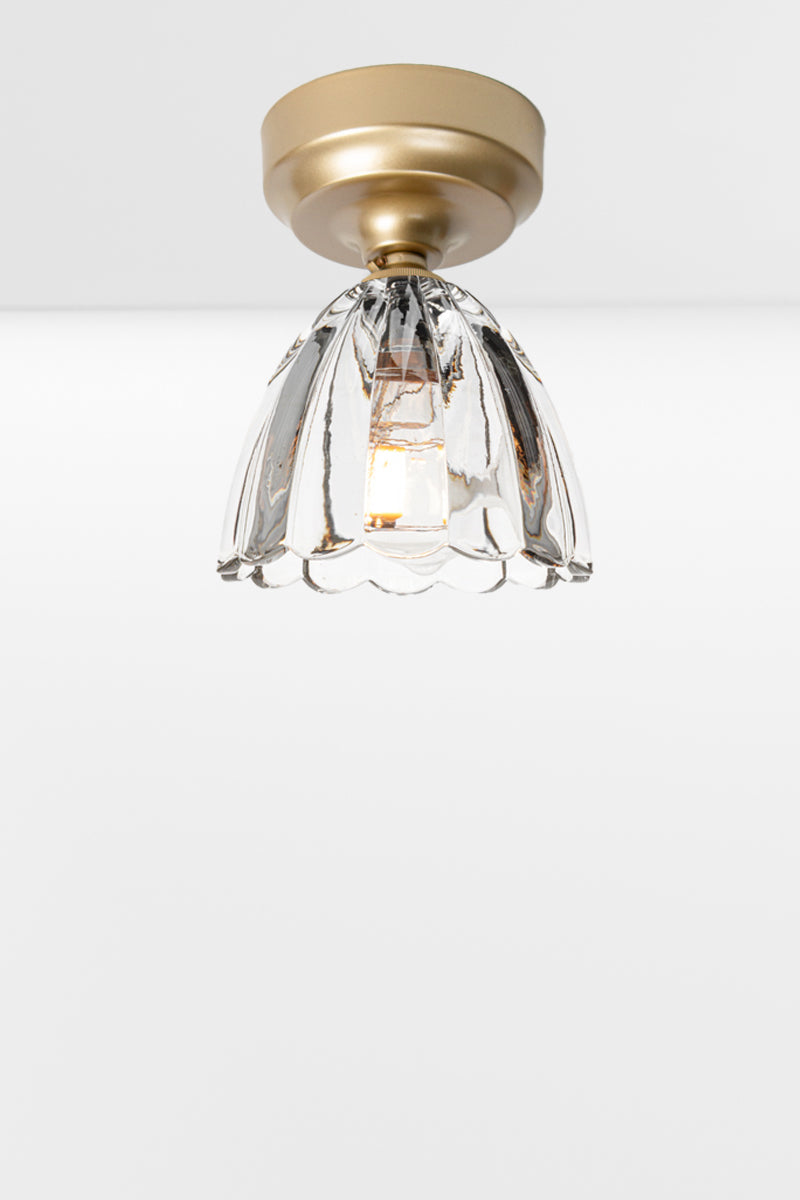 Clear glass shade with scalloped edging on a gold/brass batten holder. 