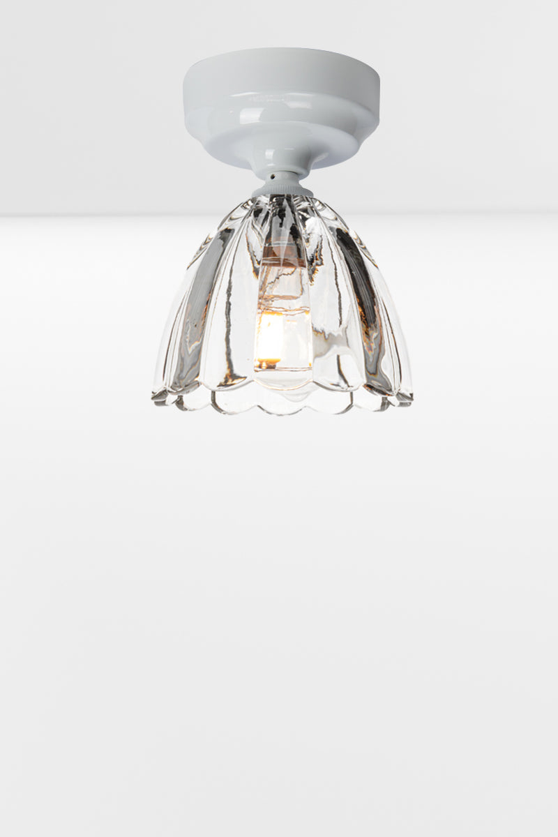 Clear glass shade with scalloped edging on a white batten holder. 