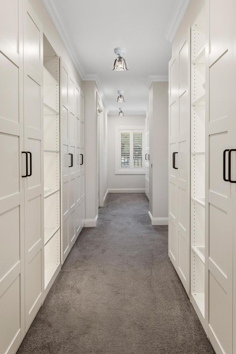 Three elegant clear glass shades on close to ceiling batten holders in a classicly finished walk in robe. 