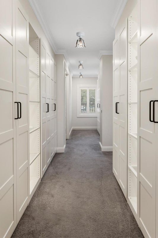 Three elegant clear glass shades on close to ceiling batten holders in a classicly finished walk in robe. 