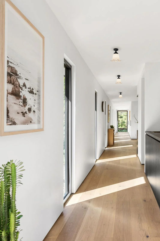Light filled hallway with three opal glass shades with scalloped edging and black batten holders. 