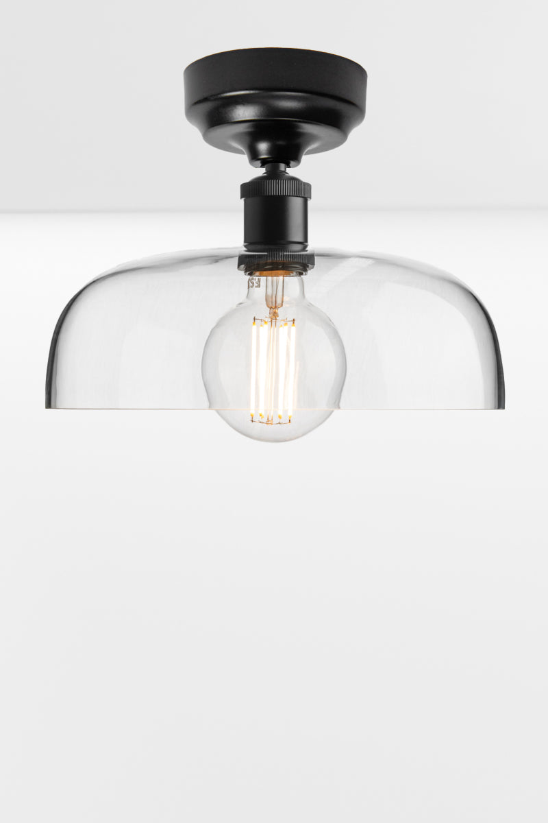 Clear glass dome shade on a black ceiling batten holder. 