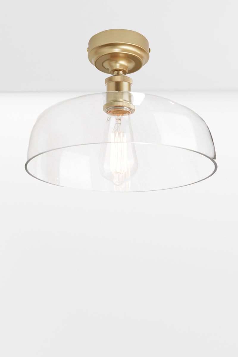 Clear glass dome shade on a gold/brass ceiling batten holder. 