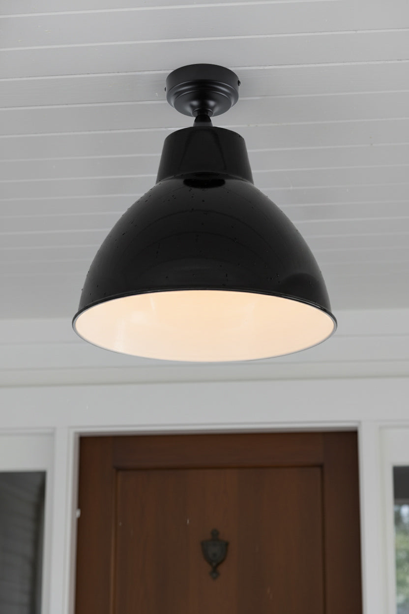 Large steel shade in black with hite inner on a flush mount ficture over a front foor. 