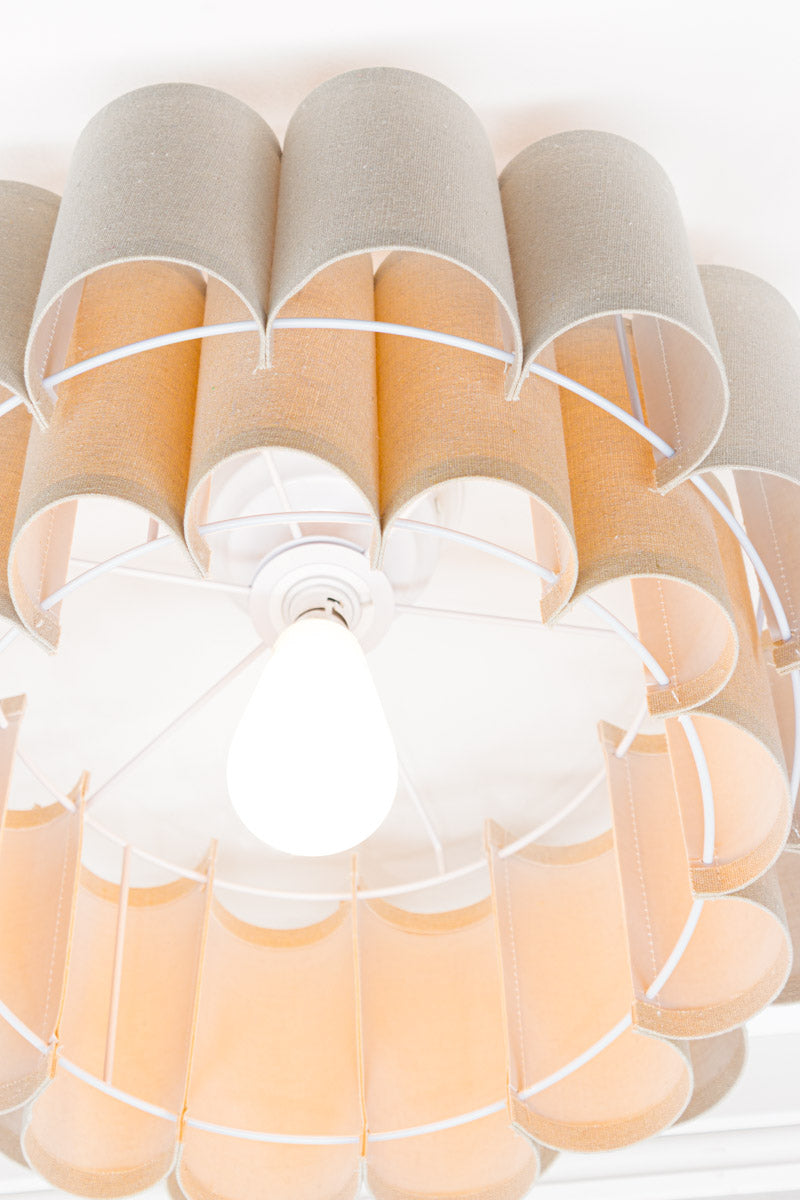 Inner view of the neutral toned fabric shade with two teirs in a scallopped formation, paired with a white batten holder.
