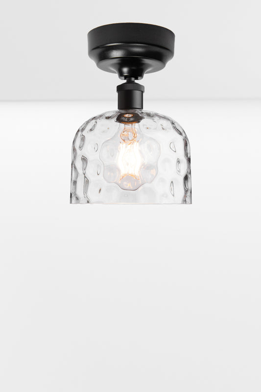 Clear glass shade with dimpled detailing paired with a black batten holder. 