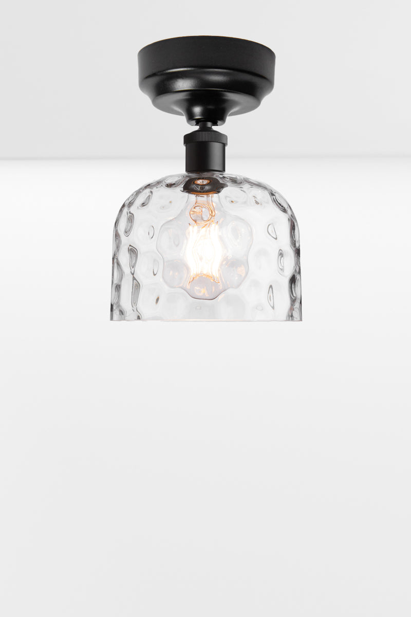 Clear glass shade with dimpled detailing paired with a black batten holder. 
