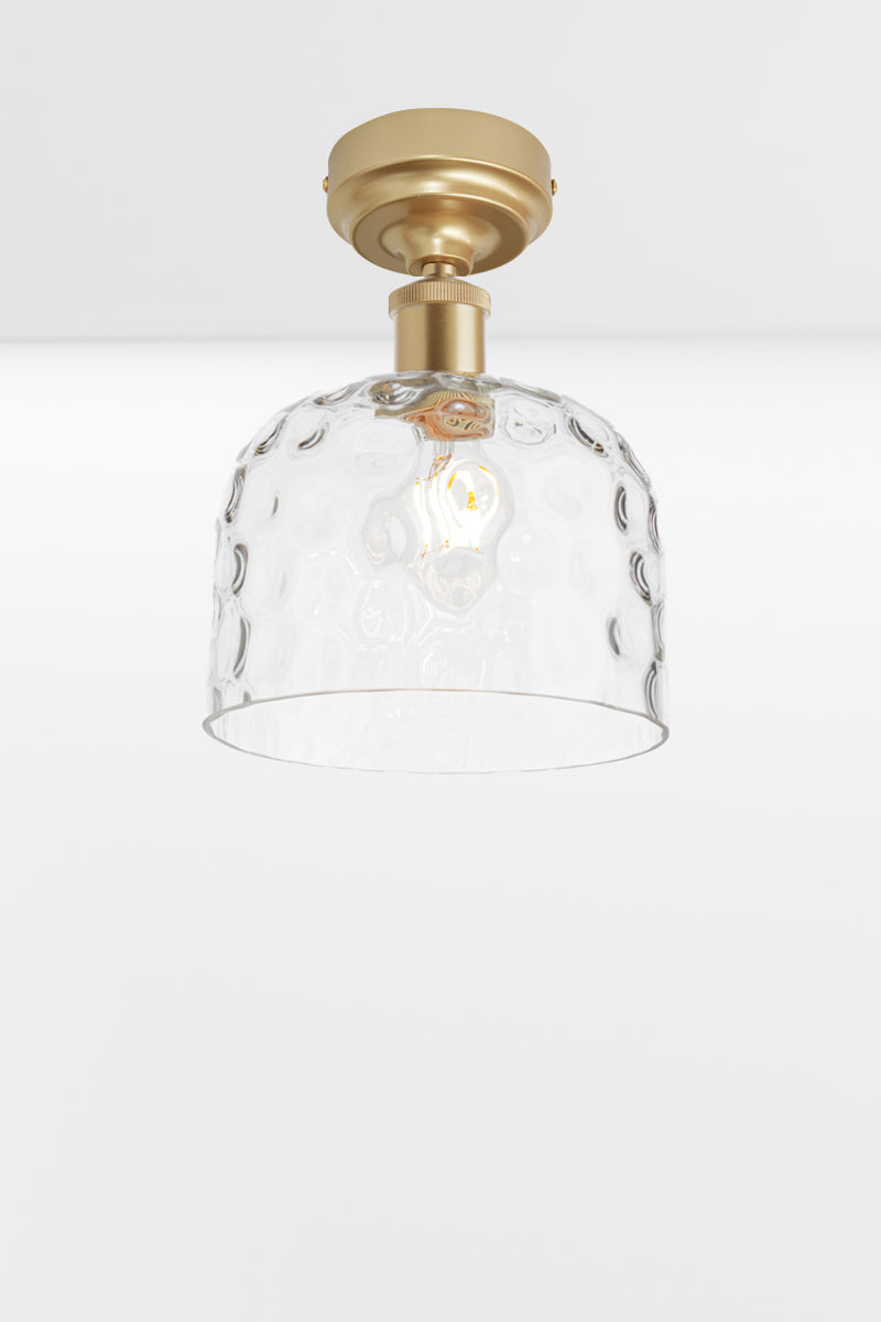 Clear glass shade with dimpled detailing paired with a gold/ brass batten holder. 