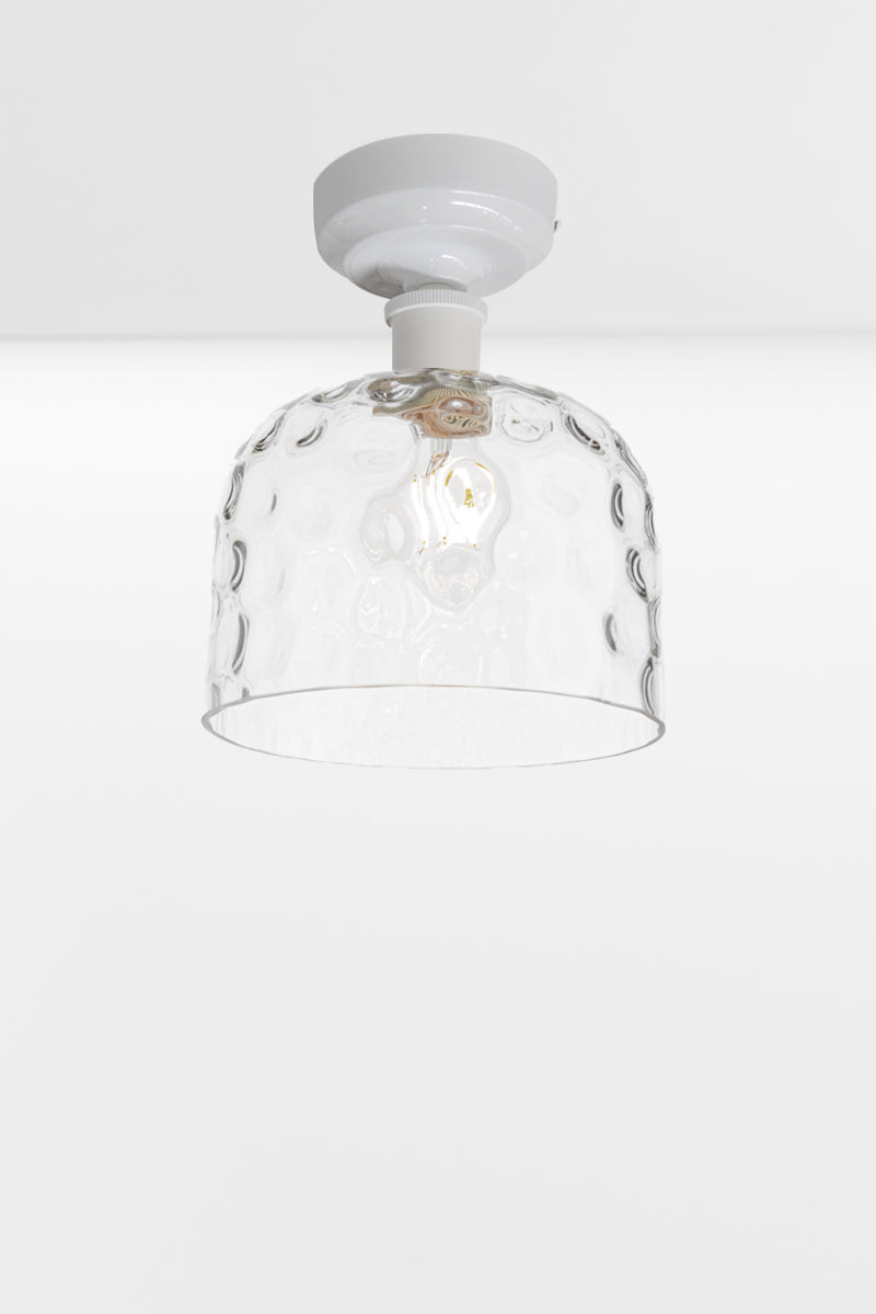 Clear glass shade with dimpled detailing paired with a white batten holder. 