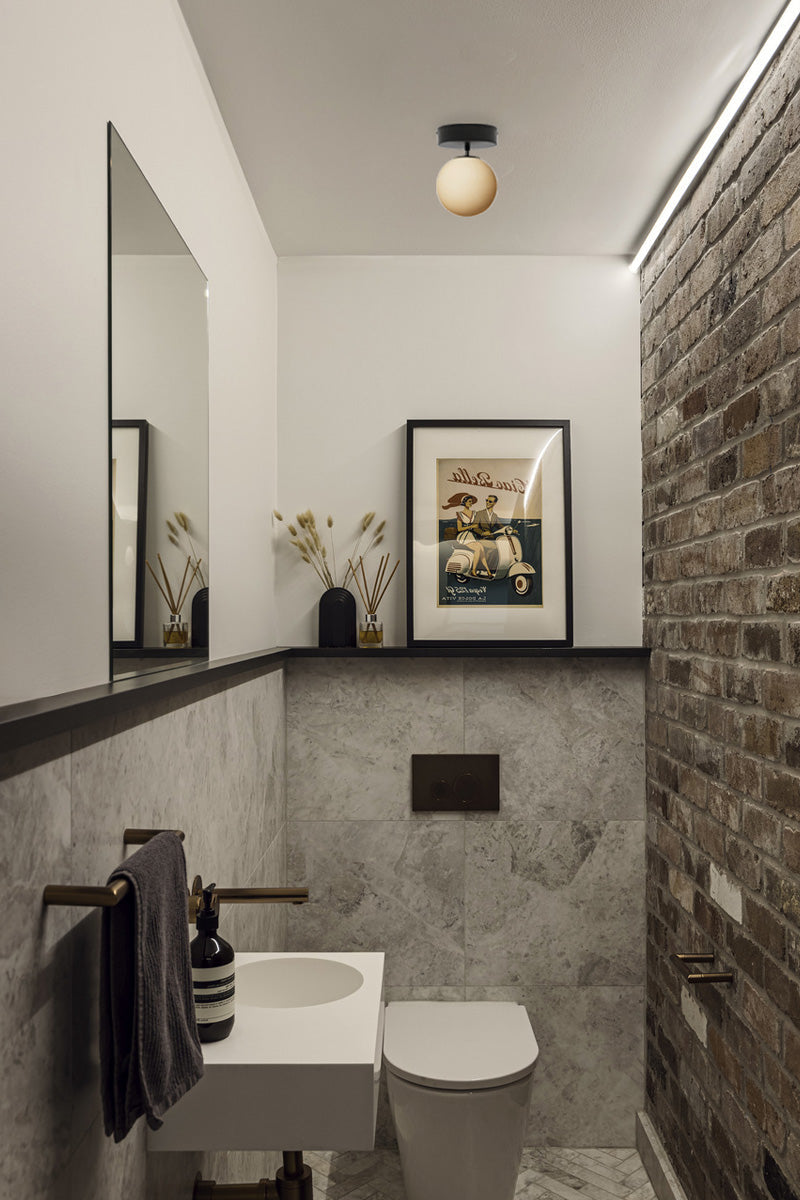 Glass ball shade on a close to ceiling-black batten holder in a textured powder room.