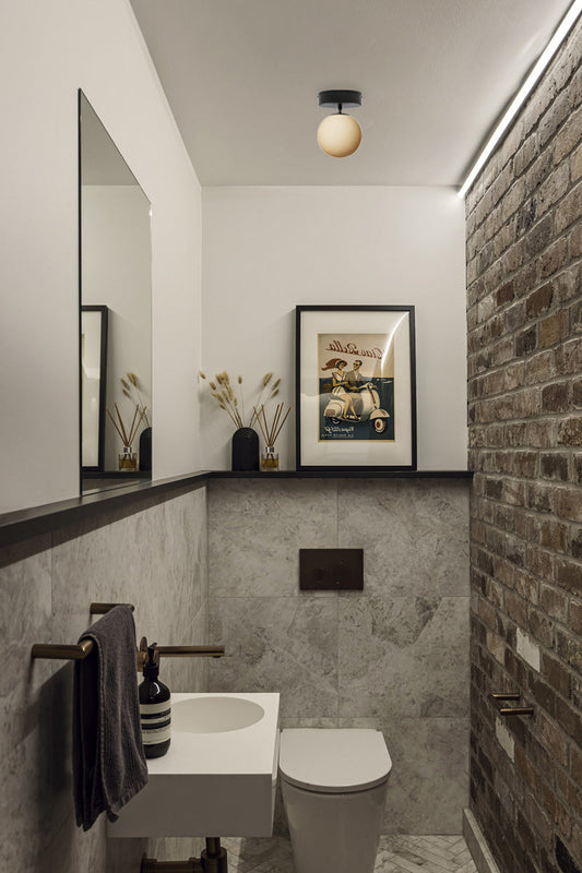 Glass ball shade on a close to ceiling-black batten holder in a textured powder room.