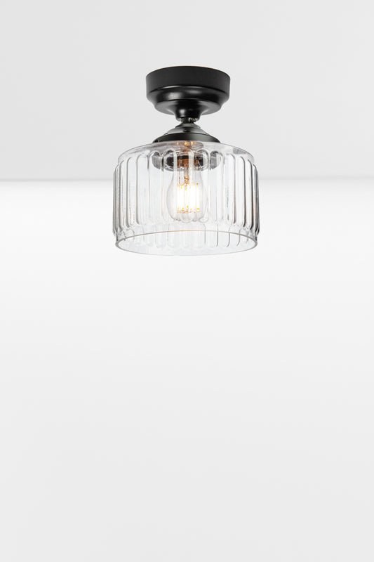 Clear glass shade with fluted detailing paired with a black batten holder and gallery. 