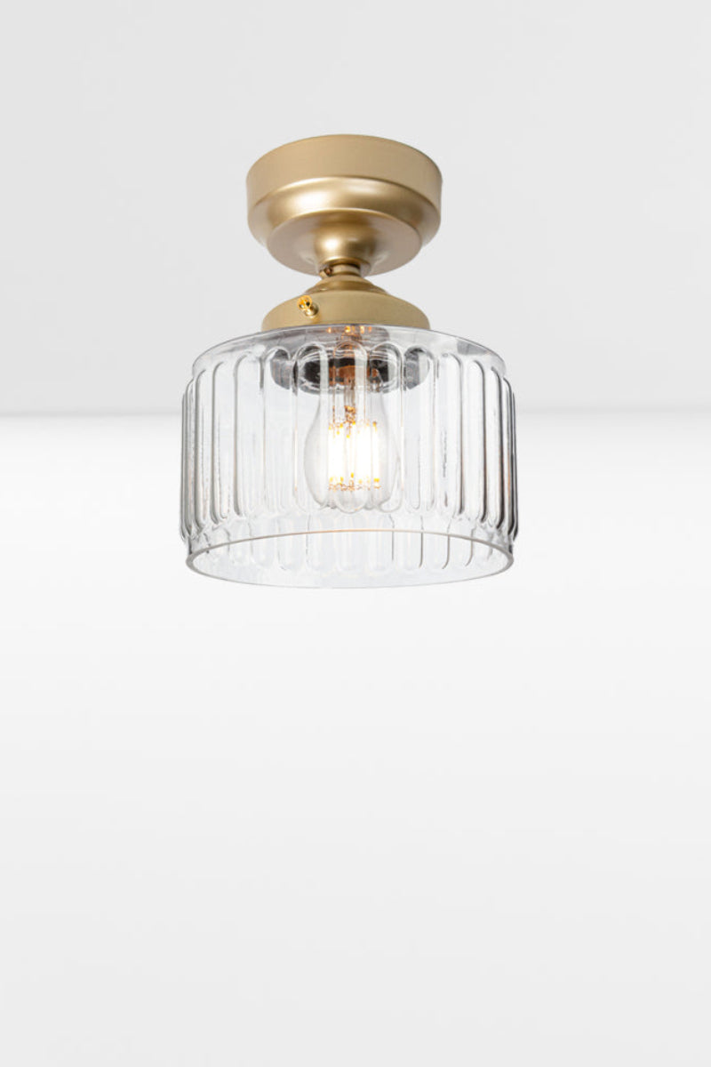 Clear glass shade with fluted detailing paired with a gold/brass batten holder and gallery. 