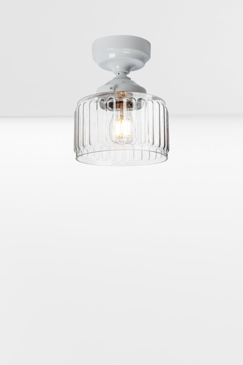 Clear glass shade with fluted detailing paired with a white batten holder and gallery. 