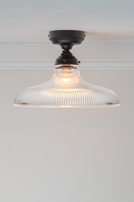 Large clear holophane glass shade on a black batten holder.