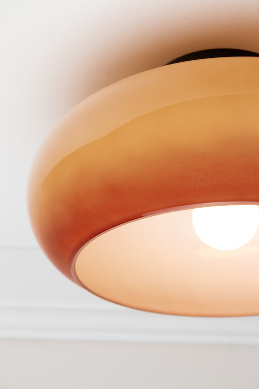 Close-up of illuminated brown Avoca Glass Ceiling Light showing tonal glass shade and white interior.