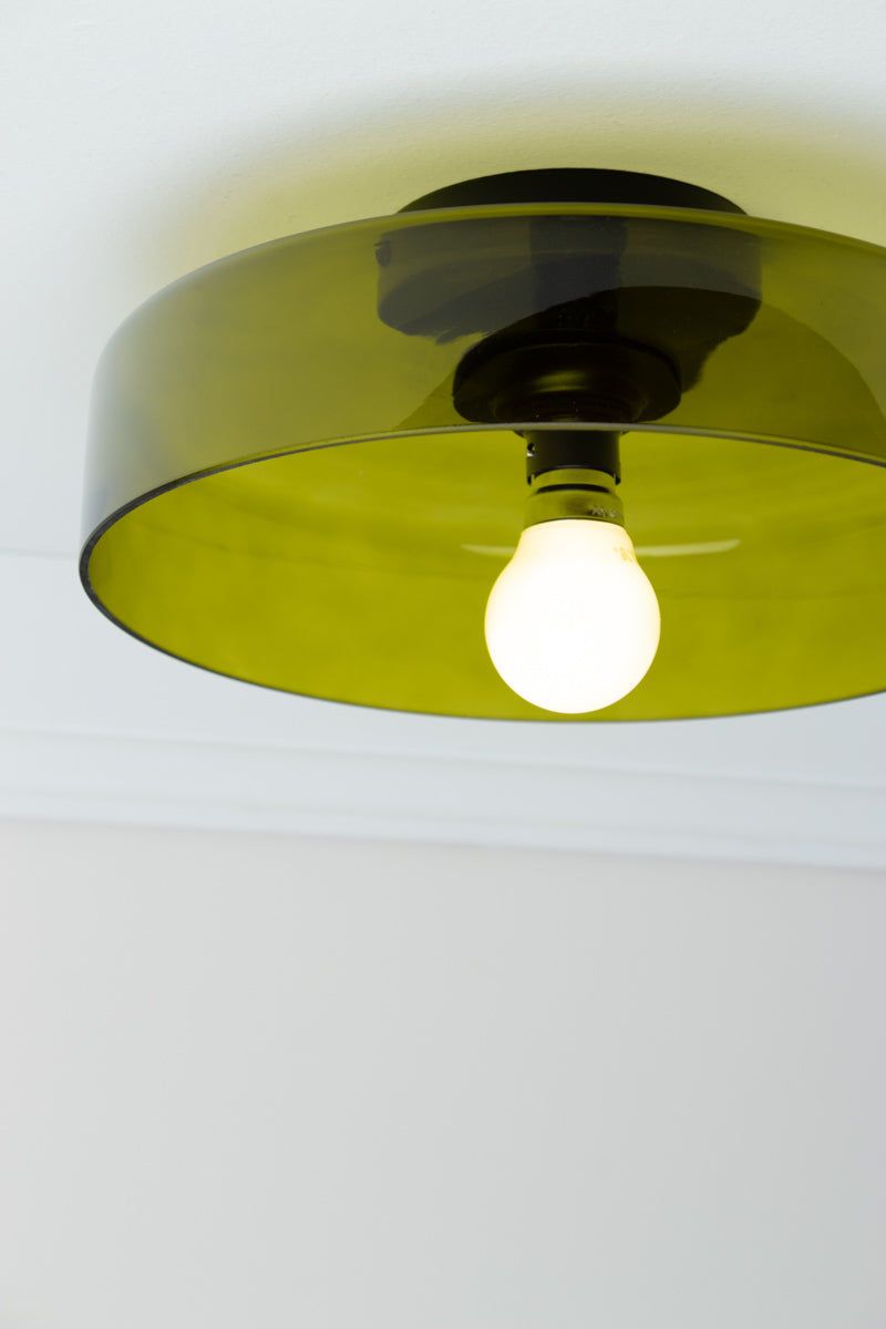 Close-up of Valla Glass Ceiling Light with transparent green glass shade and black ceiling fixture, shown illuminated.