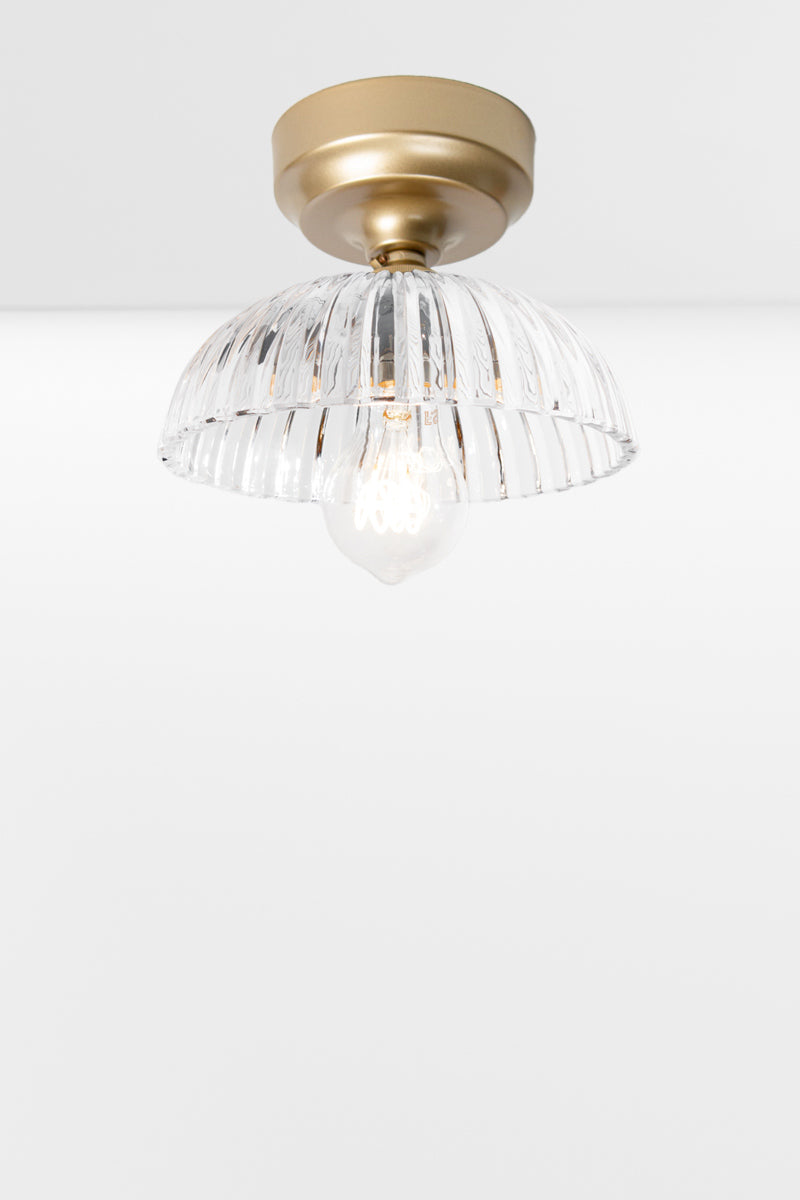 Gold/Brass batten holder paired with a clear glass shade with deep fluting and a scalloped edge. 