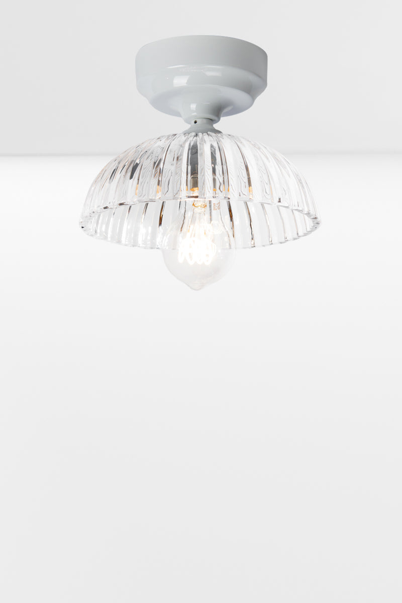 White batten holder paired with a clear glass shade with deep fluting and a scalloped edge. 