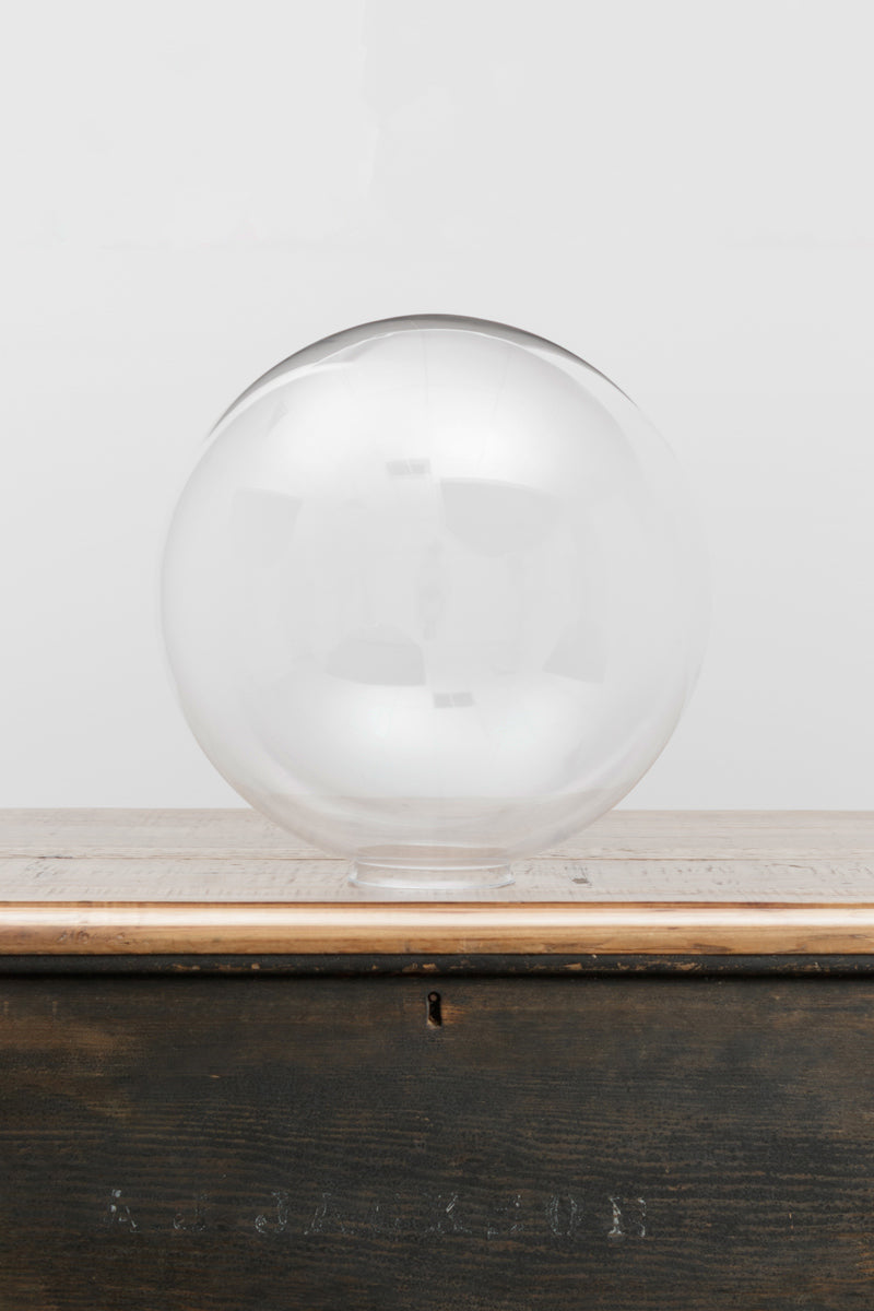 Large clear glass ball shade on a timber bench. 