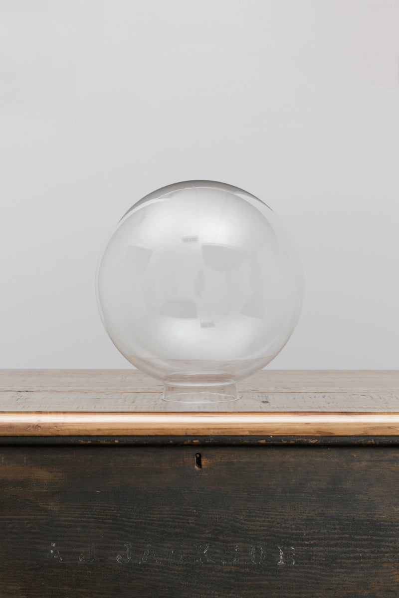Medium clear glass ball shade on a timber bench. 