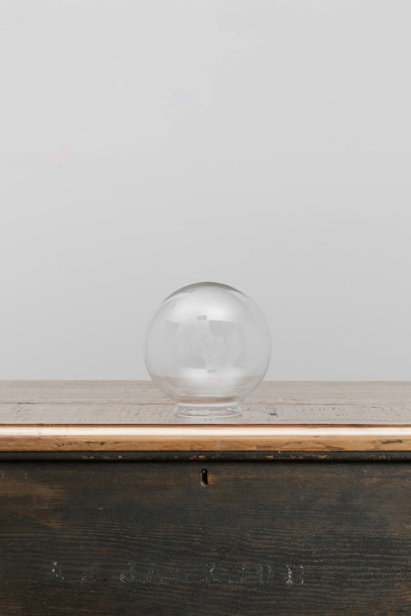 Small clear glass ball shade on a timber bench. 