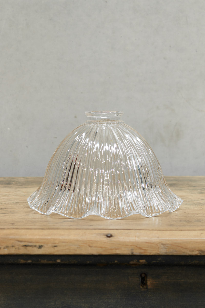 Large clear glass shade with holophane detailing and a frilled edge placed on a timber bench. 
