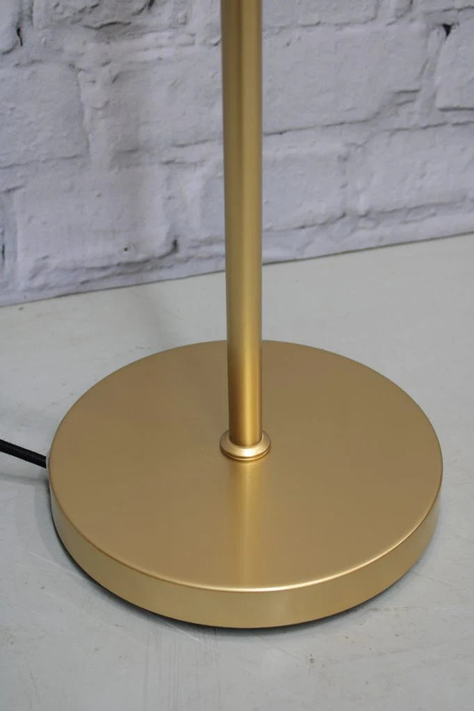 Gold floor lamp against a white brick wall.