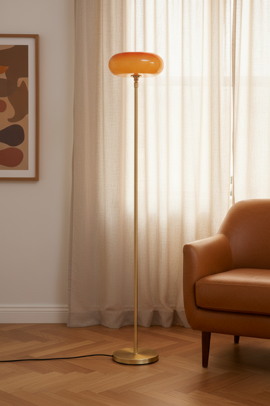 Avoca floor lamp on gold stand with brown glossy shadein a living room next to a chair