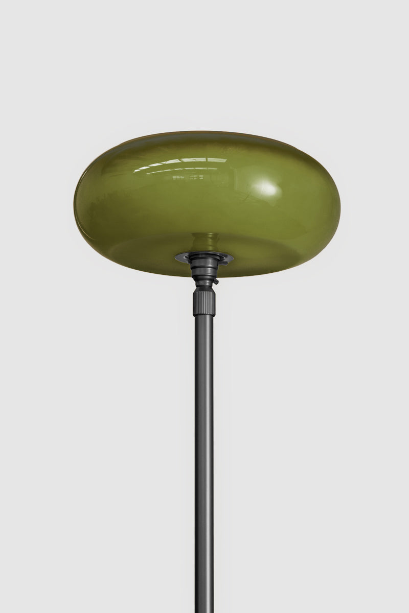 An forest green glass shade on black floor lamp